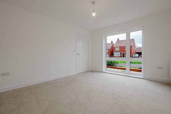 A room with a large window showing a view of houses across the street.