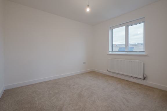 A white room with a window and a radiator on the wall.