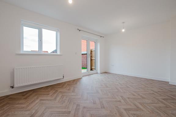 A room with a herringbone patterned floor and a white radiator.