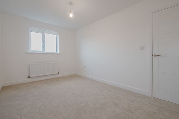 A white room with a window and a radiator on the wall.