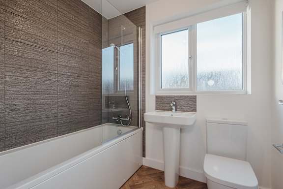 A bathroom with a white tub, sink, and toilet.