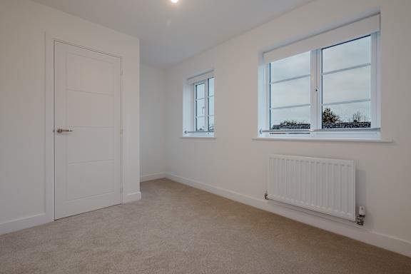 A room with a white door, window, and radiator.