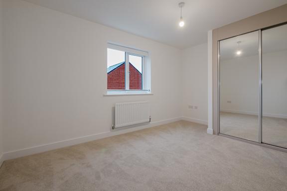 A room with a window, a radiator, and a sliding glass door.