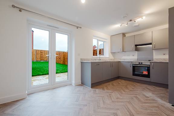 A kitchen with a white oven and wooden flooring.