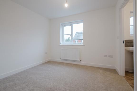 A white room with a window and a radiator on the wall.
