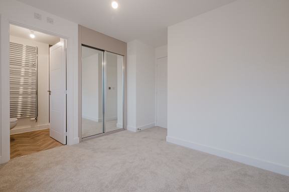 A white room with a carpeted floor and a glass door.