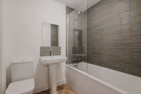 A white sink and toilet in a bathroom with a glass shower door.