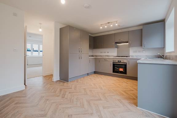 A modern kitchen with wooden flooring and stainless steel appliances.