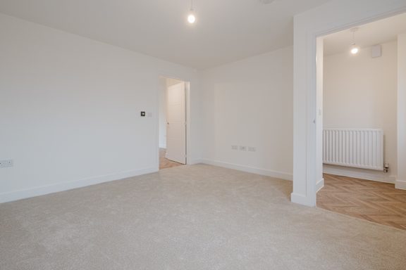A spacious room with a white wall and a radiator.
