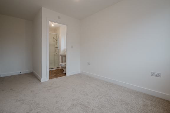 A room with a carpeted floor and a doorway leading to a bathroom.