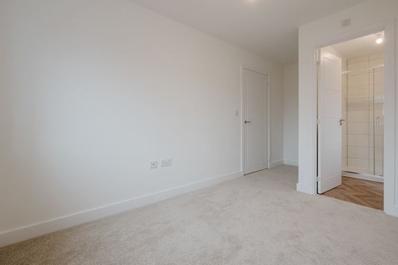 A white room with a carpeted floor and a door on the right.