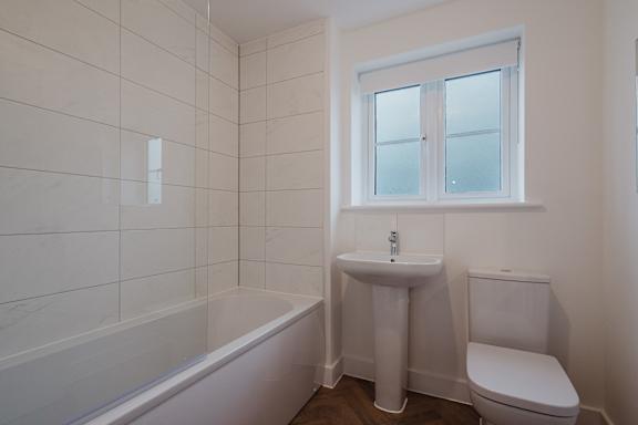 A white bathroom with a tub, sink, and toilet.