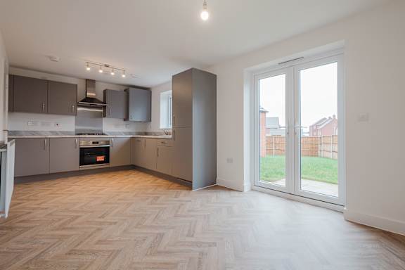 A spacious kitchen with a herringbone parquet floor and a view of the backyard through the sliding glass doors.