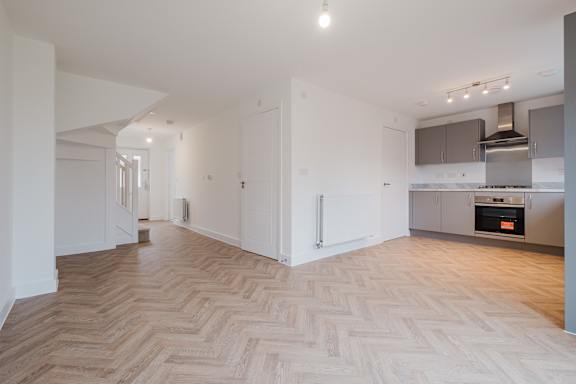 A spacious kitchen and living room with a herringbone parquet floor.