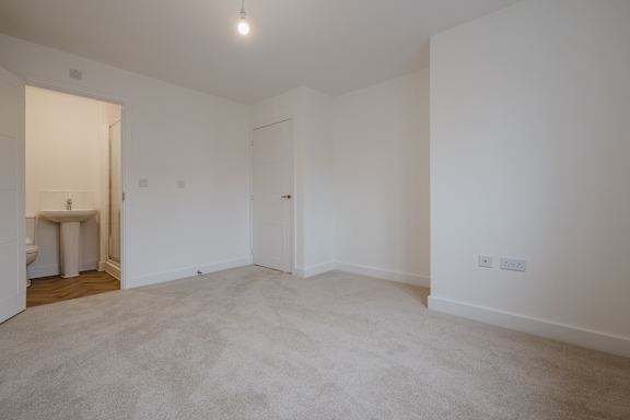 A large, empty room with a carpeted floor and white walls.