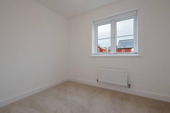 A room with a window and a radiator on the floor.