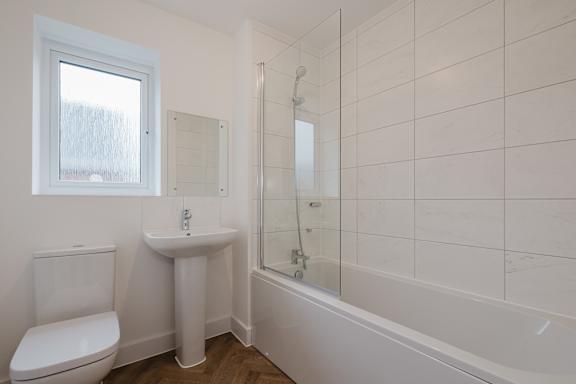 A white bathroom with a toilet, sink, and bathtub.