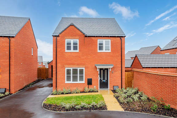 A red brick house with a grey roof and a small front yard.