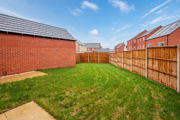 A backyard with a wooden fence and a brick building.