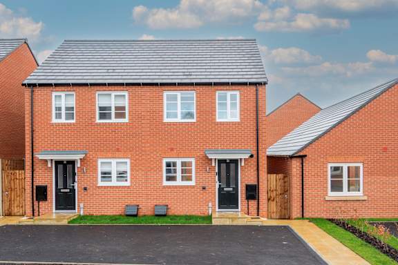 A red brick house with a grey roof and a black door.