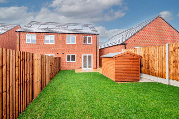 A red brick house with a wooden fence and a green lawn.