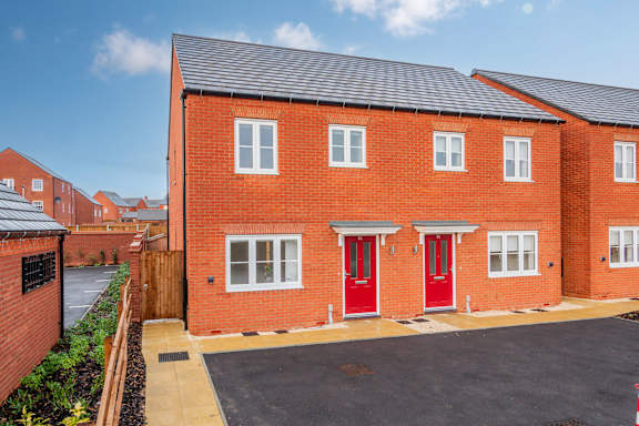 A red brick house with a black roof and a red door.