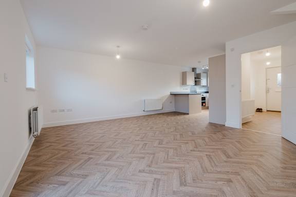 A room with a herringbone patterned floor and white walls.