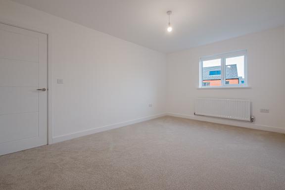 A room with a white door, a window, and a radiator.