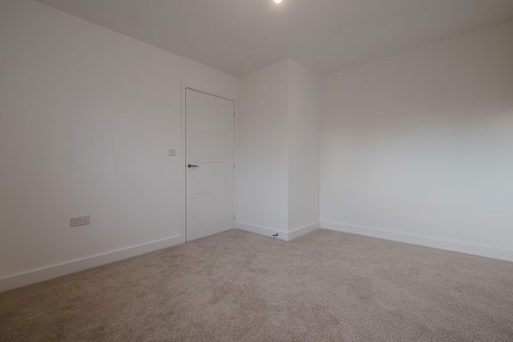 A room with a carpeted floor and a white door.