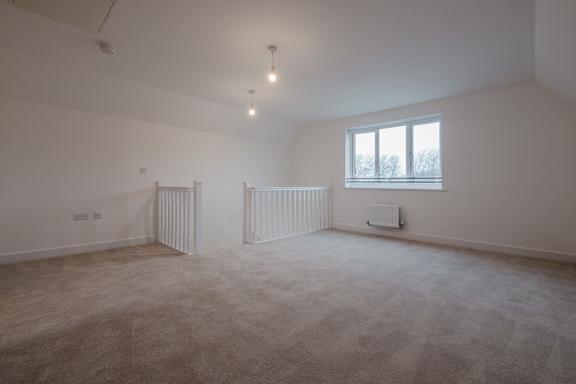 A large empty room with a window and radiator.
