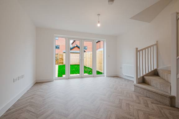A room with a wooden floor and a staircase leading to another room.