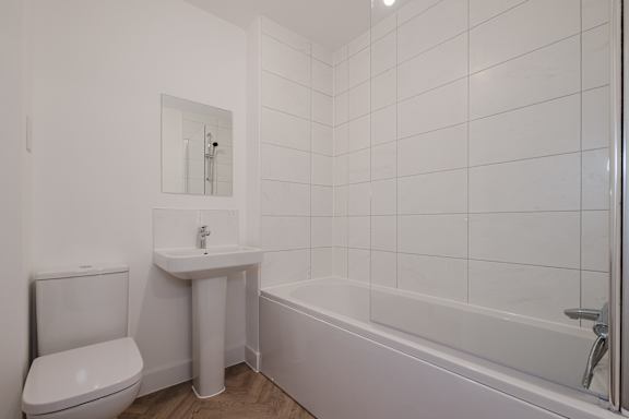A white bathroom with a toilet, sink, and bathtub.