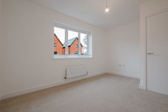 A room with a window showing a view of a red house across the way.