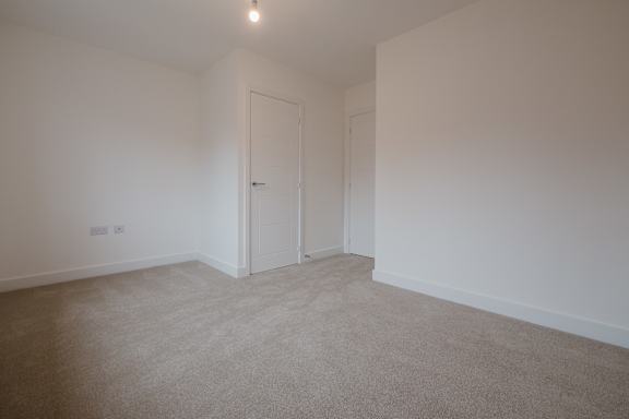 A room with a carpeted floor and a white door.