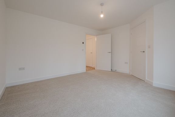 A room with a carpeted floor and two doors.