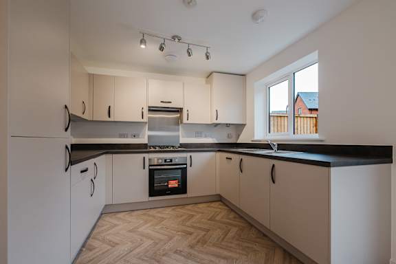 A kitchen with wooden flooring and white walls.
