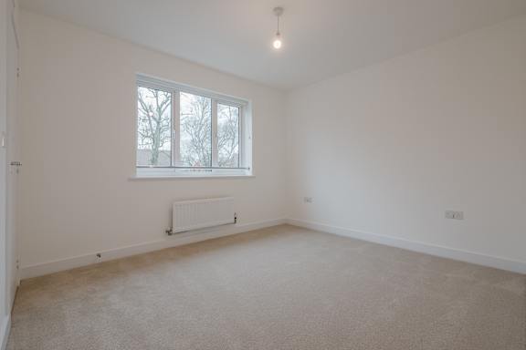 A white room with a window and a radiator on the wall.