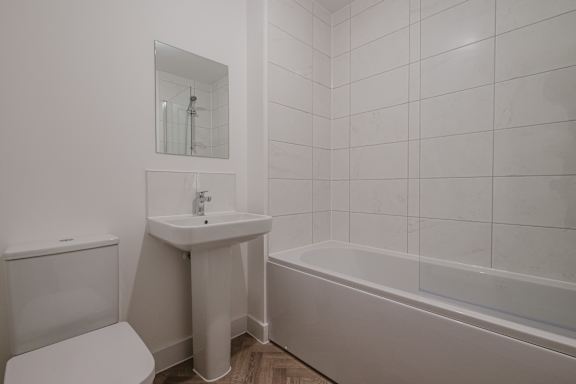 A white bathroom with a toilet, sink, and bathtub.