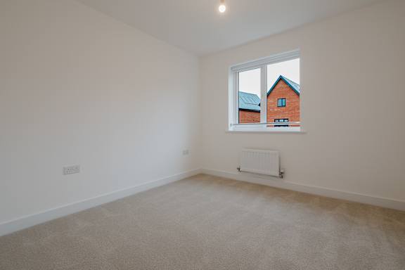 A room with a window showing a view of a red house.