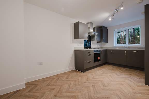 A kitchen with wooden flooring and a window.