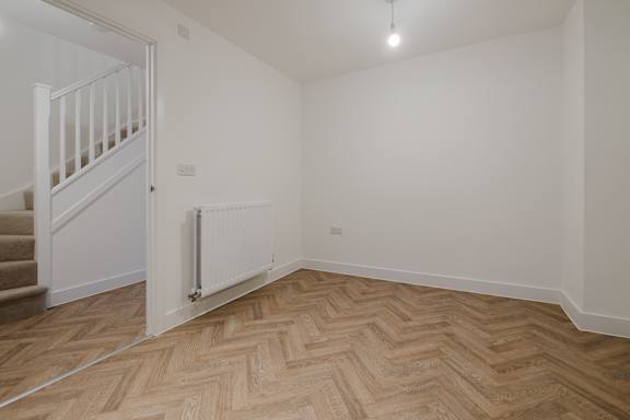 A room with a wooden floor and a white wall.