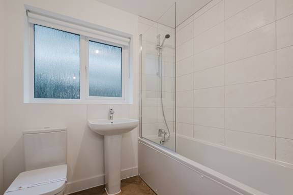 A white bathroom with a toilet, sink, and bathtub.
