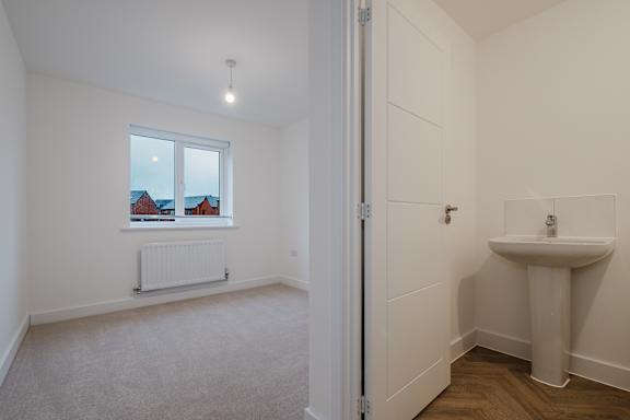 A white bathroom with a window and a sink.