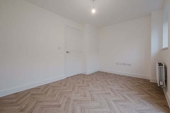 A room with a herringbone patterned floor and a white door.