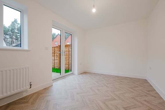 A room with a wooden floor and a window overlooking a backyard.