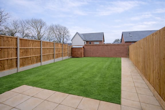 A backyard with a wooden fence and a green lawn.