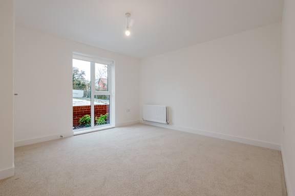 A white room with a window and a radiator on the wall.