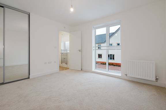 A room with a carpeted floor, a sliding glass door, and a white wall.