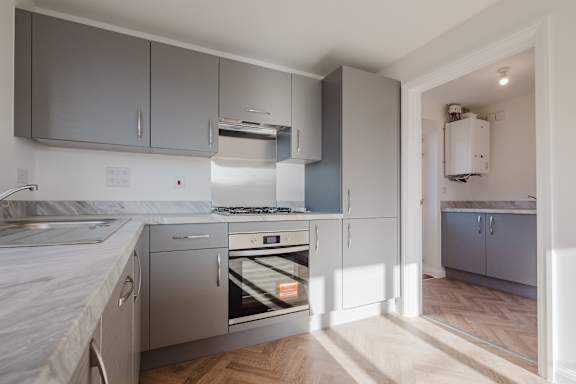 A modern kitchen with stainless steel appliances and wooden flooring.