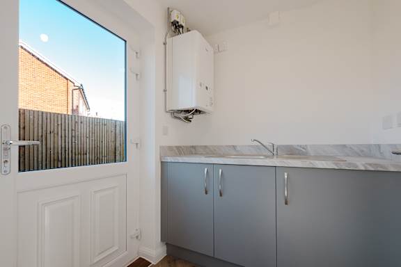 A kitchen with a window, sink, and cabinets.